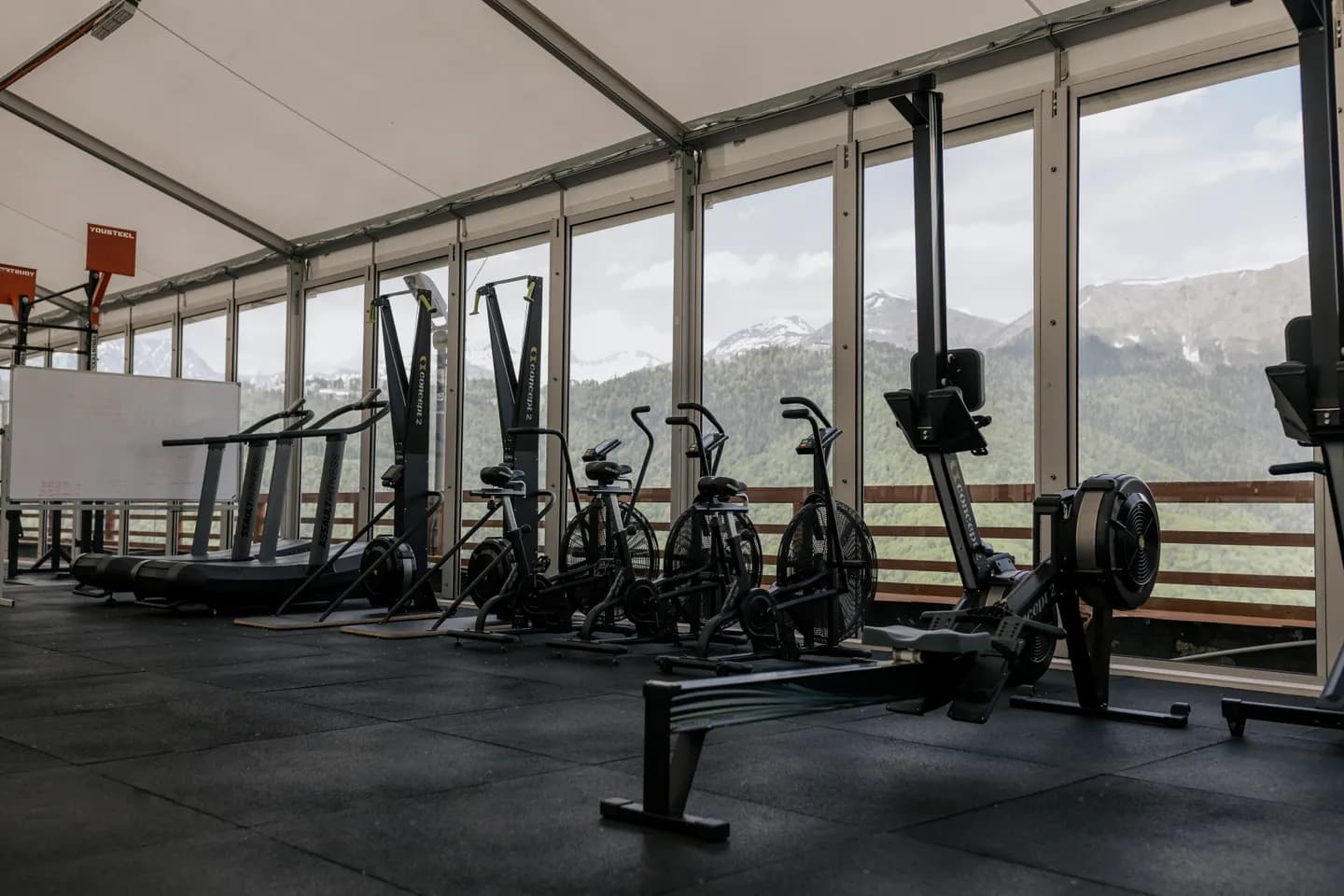 Interior de un gimnasio con equipos de entrenamiento junto a grandes ventanales